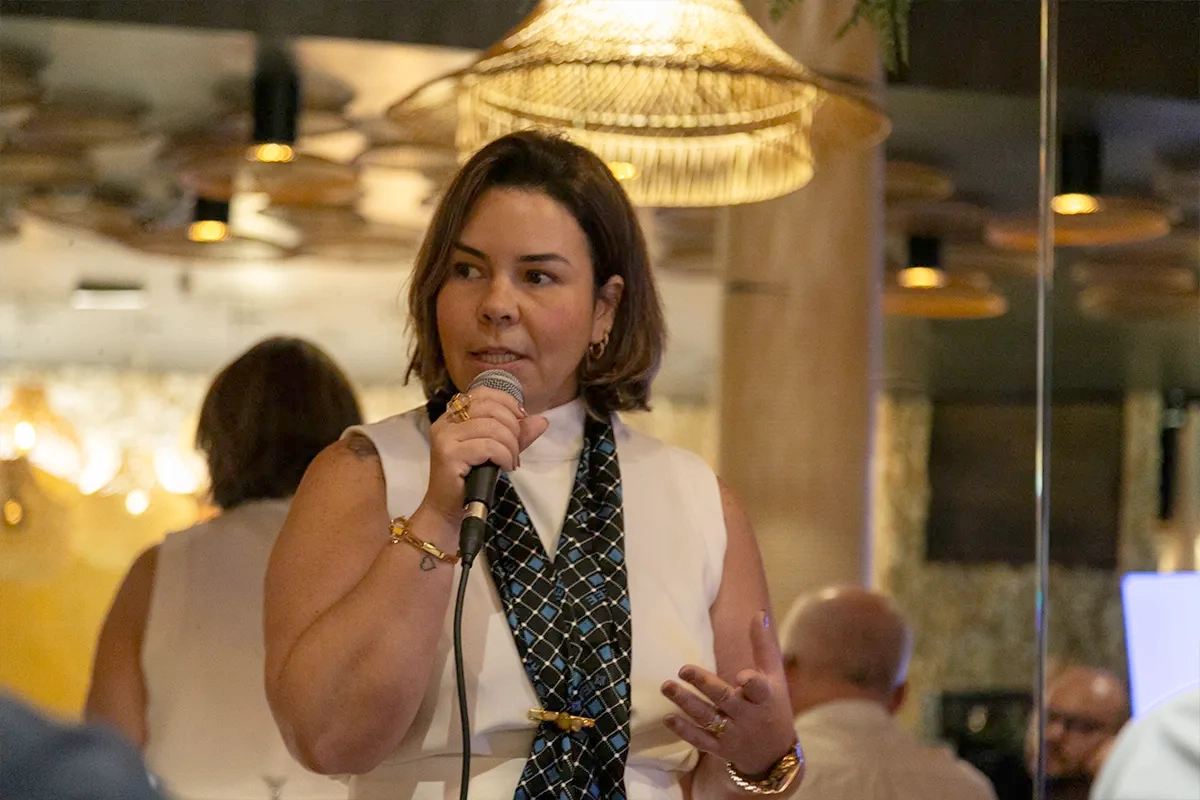 Impact Creator Cristiane Pimentel speaks during an IEEE dinner party at Futurecom 2025 about the importance of IEEE and its dedication to advancing technology for the benefit of humanity