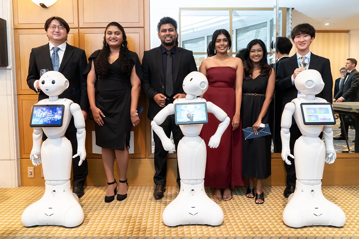 Young professionals pose with robots that were on site