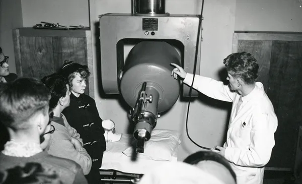 Tech/professor/doctor demonstrating how to use the Cobalt-60 machine to a group of students